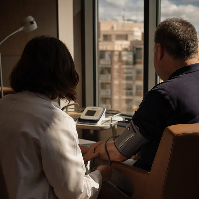 A doctor taking a patient blood pressure in a city clinic consulting room